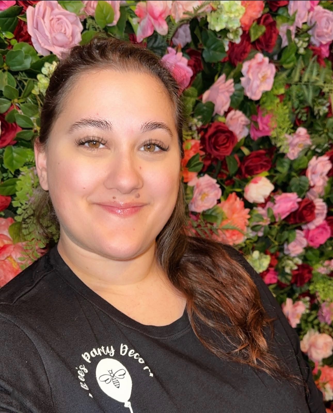 Brittany, owner of Bee's Party Decor, in front of a pink and red floral wall
