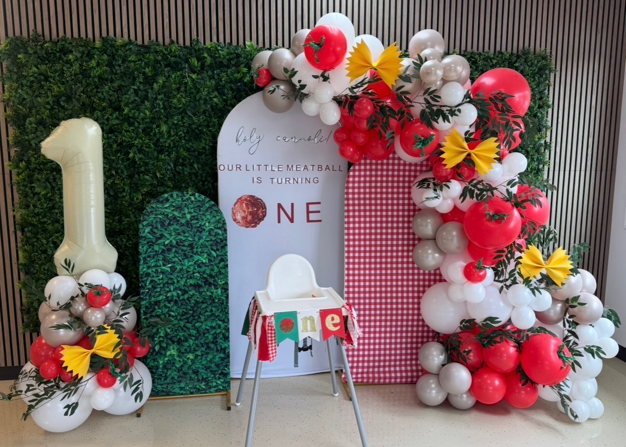 Italian-themed first birthday balloon arch with tomatoes, pasta bows and gingham